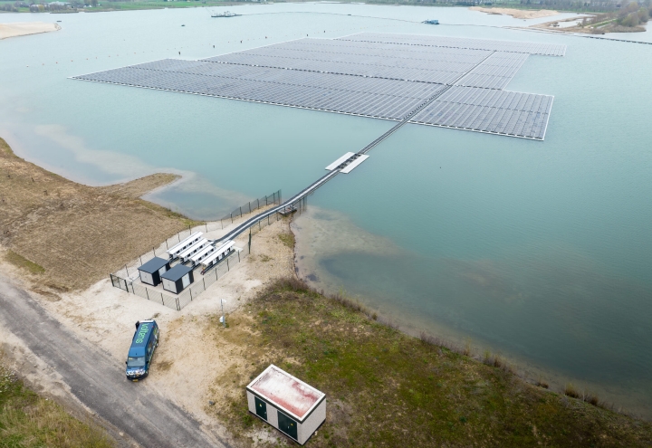 Luchtfoto van een drijvend zonnepark met transformatorstations aan de oever