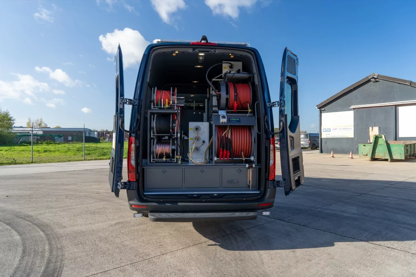 Achteraanzicht van een geopende bestelbus met kabelhaspels en gereedschap